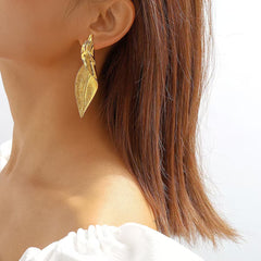 Elegant woman accessorising with leaf earrings